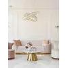 Sofa Beżowa Glamour Aksamitna FLORENCE Złote Nogi umiejscowiona przy oknie, w jasnym wnętrzu od Primavera Home.