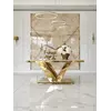Stół glamour LV Collection z białym blatem i złotą podstawą, ustawiony centralnie w jasnym, przestronnym wnętrzu z marmurową ścianą i wiszącymi lampami.