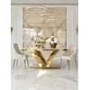 Stół glamour LV Collection z białym blatem i złotą podstawą, ustawiony przy dwóch kremowych krzesłach na tle dekoracyjnej ściany.