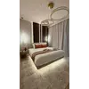 Żyrandol Crystal XXL z trzema ringami nad łóżkiem, na tle jasnego dywanu oraz zasłon w sypialni.