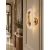 Zbliżenie na kinkiet złoty, nowoczesny, prezentujący elegancki wygląd w aranżacji. Oferowany przez Primavera Home.