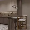 Dwa beżowe hokery Romeo przy marmurowej wyspie kuchennej ze złotymi dodatkami