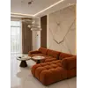 Aranżacja z imprezą w tle przy designerskim narożniku modułowym boucle NICEA. Meble na zamówienie od Primavera Home.