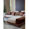 Sofa narożna z półką umieszczona przy oknie, tworząca jasną i przestronną atmosferę od Primavera Home.