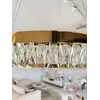 Złoty Żyrandol Kryształowy Bellini ukazany z boku, podkreślający jego elegancki design. Aranżacja nowoczesnego wnętrza od Primavera Home.