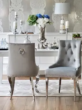 Luksusowe krzesło glamour, pikowane z kołatką, do jadalni, na stalowych, prostych nogach, szare, srebrne MADAME w ujęciu z przodu. Oświetlenie na zamówienie od Primavera Home.