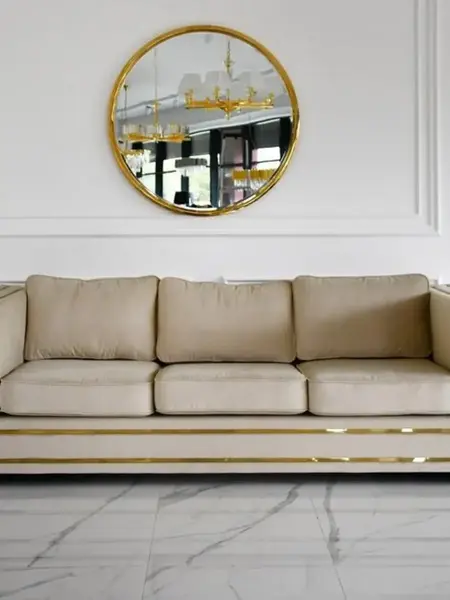 Sofa umieszczona w jasnym wnętrzu, podkreślająca styl glamour. Meble na zamówienie od Primavera Home.