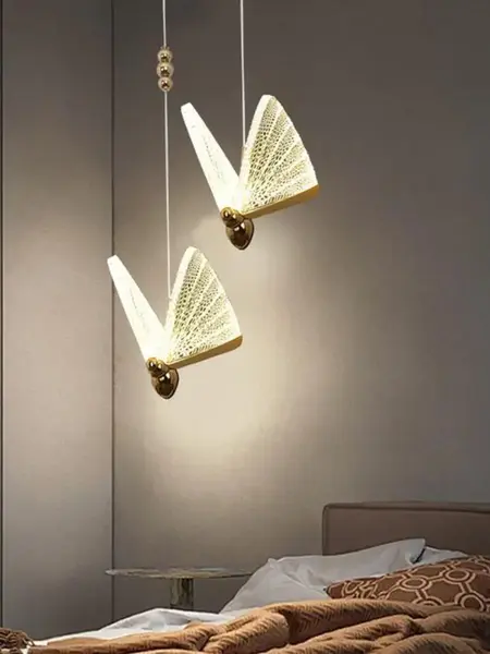 Żyrandol Motyl M Złoty umieszczony przy ścianie, dodający elegancji pomieszczeniu. Aranżacja nowoczesnego wnętrza od Primavera Home.