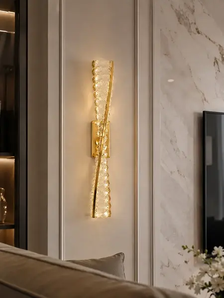 Kinkiet Kryształowy Złoty Podłużny Crystal w jasnym wnętrzu, rozświetlający przestrzeń. Ekspozycja w salonie od Primavera Home.