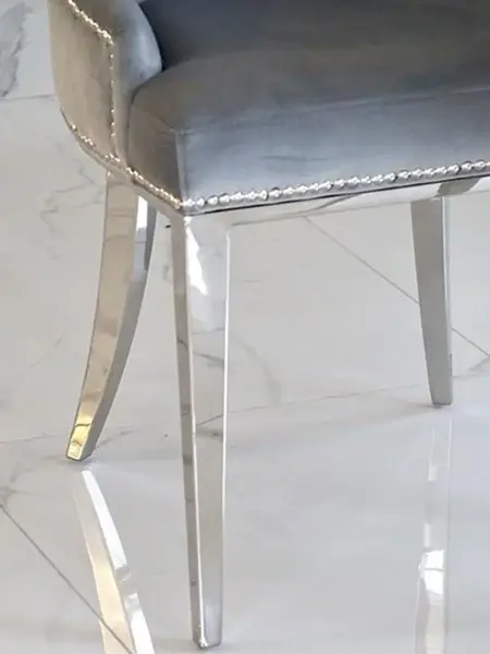Luksusowe krzesło glamour, pikowane z kołatką, do jadalni, na stalowych, prostych nogach, szare, srebrne MADAME uchwycone w eleganckim ujęciu. Meble na zamówienie od Primavera Home.
