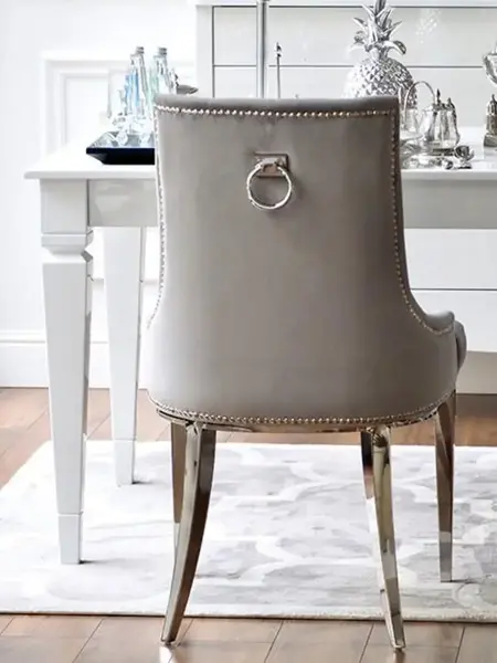 Luksusowe krzesło glamour, pikowane z kołatką, do jadalni, na stalowych, prostych nogach, szare, srebrne MADAME w perspektywie, ujawniające jego elegancję. Aranżacja nowoczesnego wnętrza od Primavera Home.
