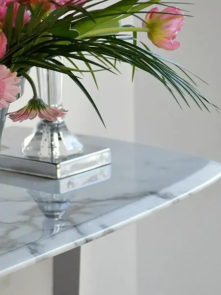 Zbliżenie na krawędzie konsoli w stylu nowoczesnym glamour z białym marmurowym blatem srebrna ART DECO, podkreślające jej elegancję. Meble na zamówienie od Primavera Home.