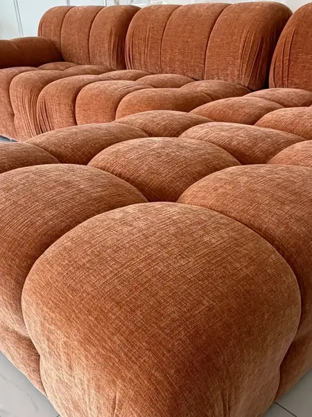 Stylizacja z książką obok designerskiego narożnika modułowego boucle NICEA. Meble na zamówienie od Primavera Home.