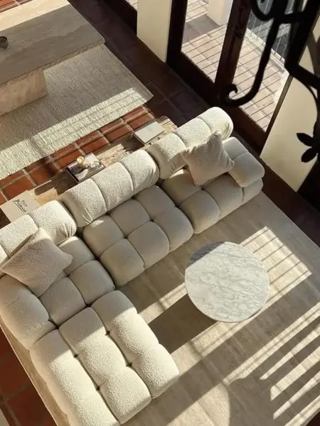 Widok nocny z designerskim narożnikiem modułowym boucle NICEA w nowoczesnym salonie. Oferowane przez Primavera Home.