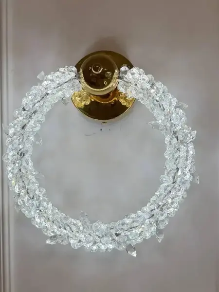 Kinkiet Kryształowy ICE ROUND widoczny pod kątem, co ukazuje jego finezyjny styl. Ekskluzywne oświetlenie od Primavera Home.