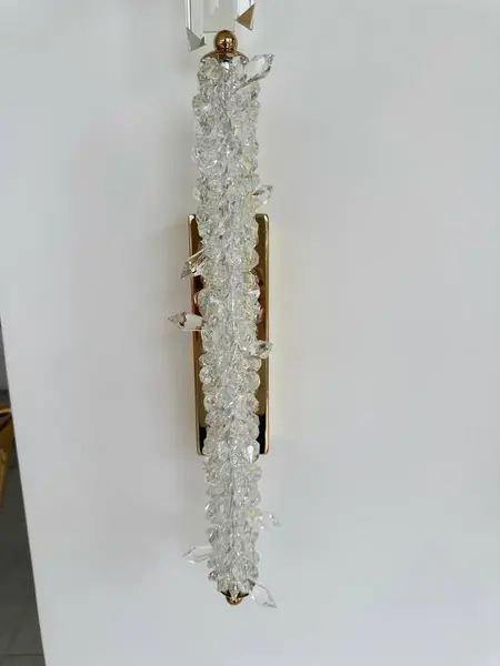Zbliżenie na detale kryształowego kinkietu. Elegancka struktura w aranżacji nowoczesnego wnętrza od Primavera Home.