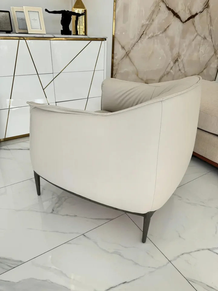 Detal wykończenia Nowoczesnego wygodnego fotela luksusowego do salonu z podnóżkiem MODERN, podkreślający jego elegancję. Oświetlenie od Primavera Home.