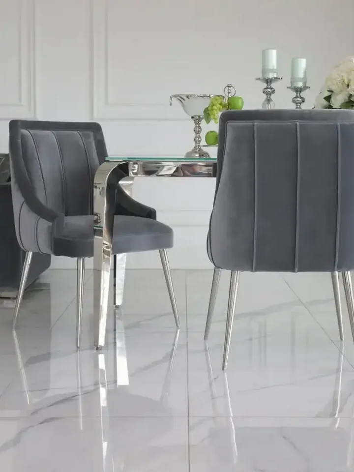 Bliskie ujęcie designerskiego stołu glamour ze szklanym blatem, stalowego, nowoczesnego, srebrnego ELITE, oświetlonego naturalnym światłem, oferowanego przez Primavera Home.
