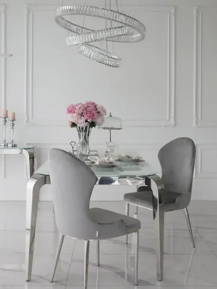 Ekspozycja w mieszkaniu z designerskim stołem glamour ze szklanym blatem, stalowym, nowoczesnym, srebrnym ELITE, idealnym dla miłośników stylu od Primavera Home.