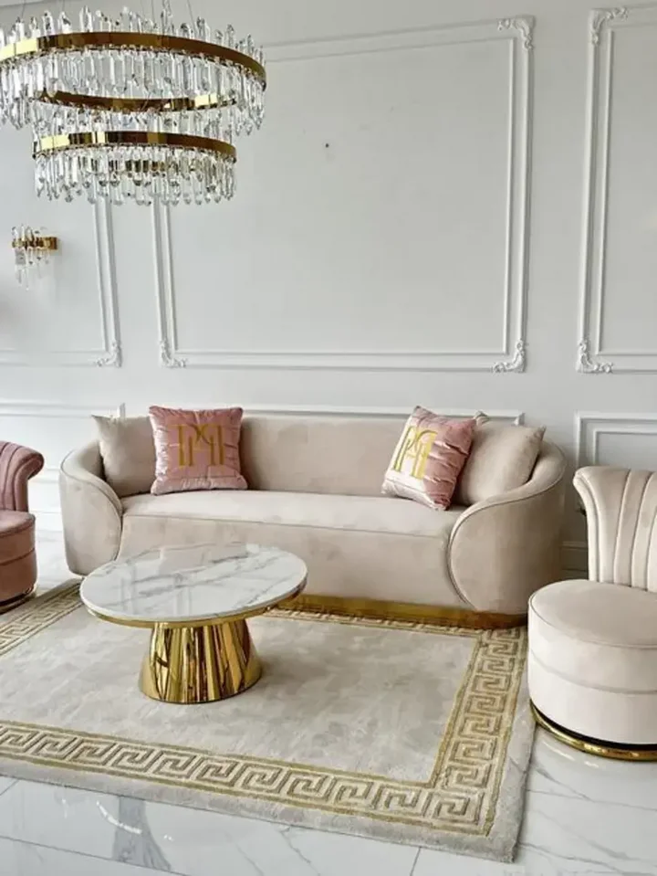 Sofa Beżowa Glamour Aksamitna FLORENCE Złote Nogi w otoczeniu roślin, tworząca przytulny klimat od Primavera Home.