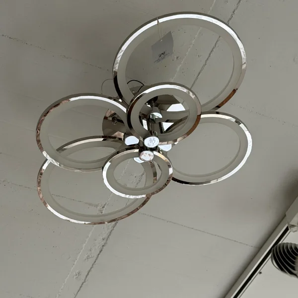 Lampa sufitowa LED Cerchio w srebrze, pokazana z boku na tle surowego, technicznego sufitu z widoczną instalacją.