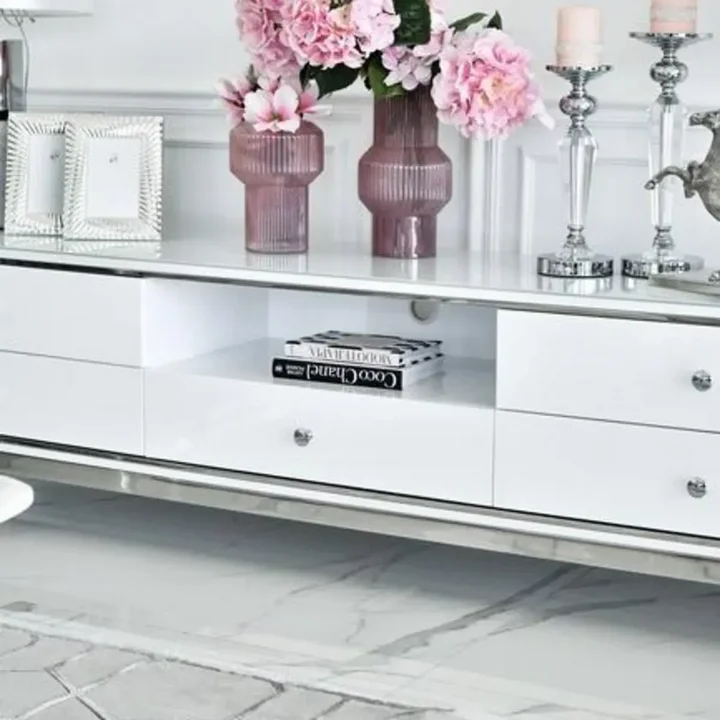 Komoda RTV glamour wysoki połysk biało srebrna Lorenzo L Silver na tle szarej ściany. Meble na zamówienie od PRIMAVERA HOME.
