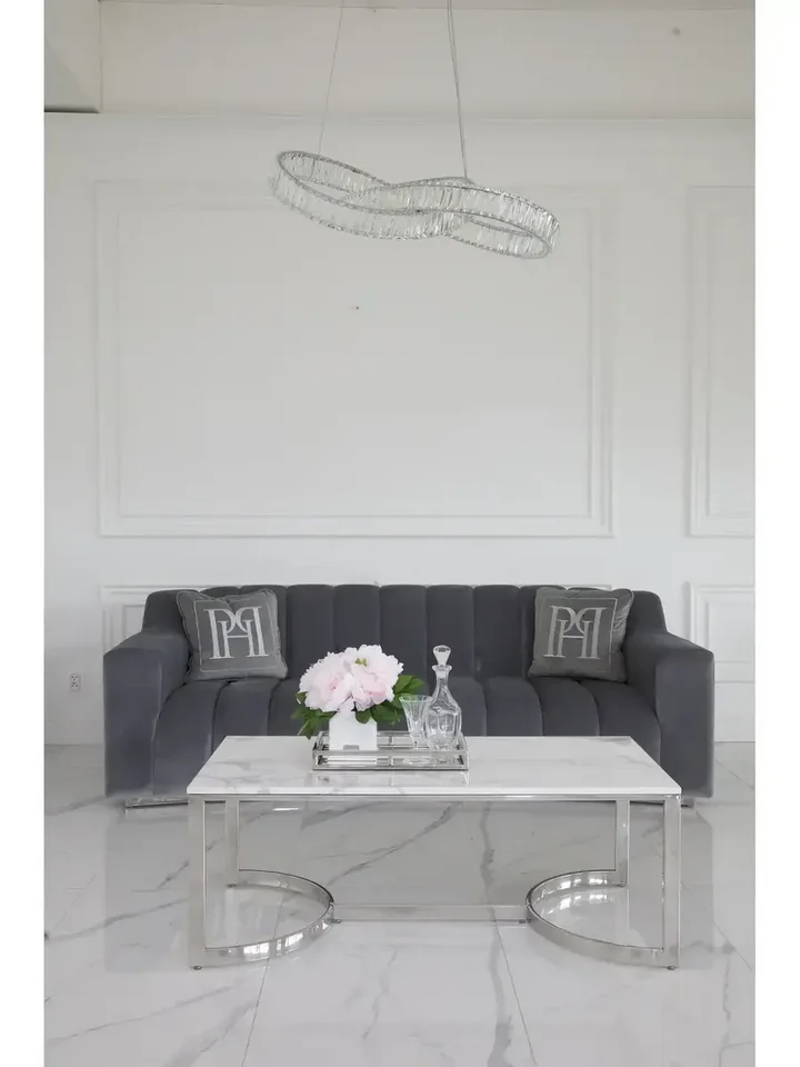 Widok z boku stolika kawowego Lola srebrnego z białym blatem w eleganckim wnętrzu. Meble na zamówienie od PRIMAVERA HOME.