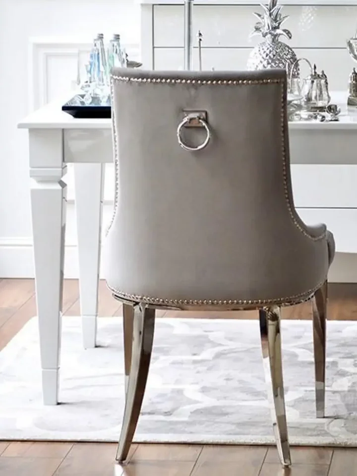 Luksusowe krzesło glamour, pikowane z kołatką, do jadalni, na stalowych, prostych nogach, szare, srebrne MADAME w perspektywie, ujawniające jego elegancję. Aranżacja nowoczesnego wnętrza od Primavera Home.