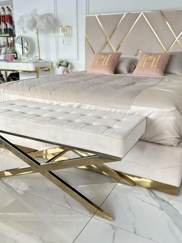Zbliżenie na złote krzyżakowe nóżki pufy, podkreślające jej elegancję. Propozycja od Primavera Home.