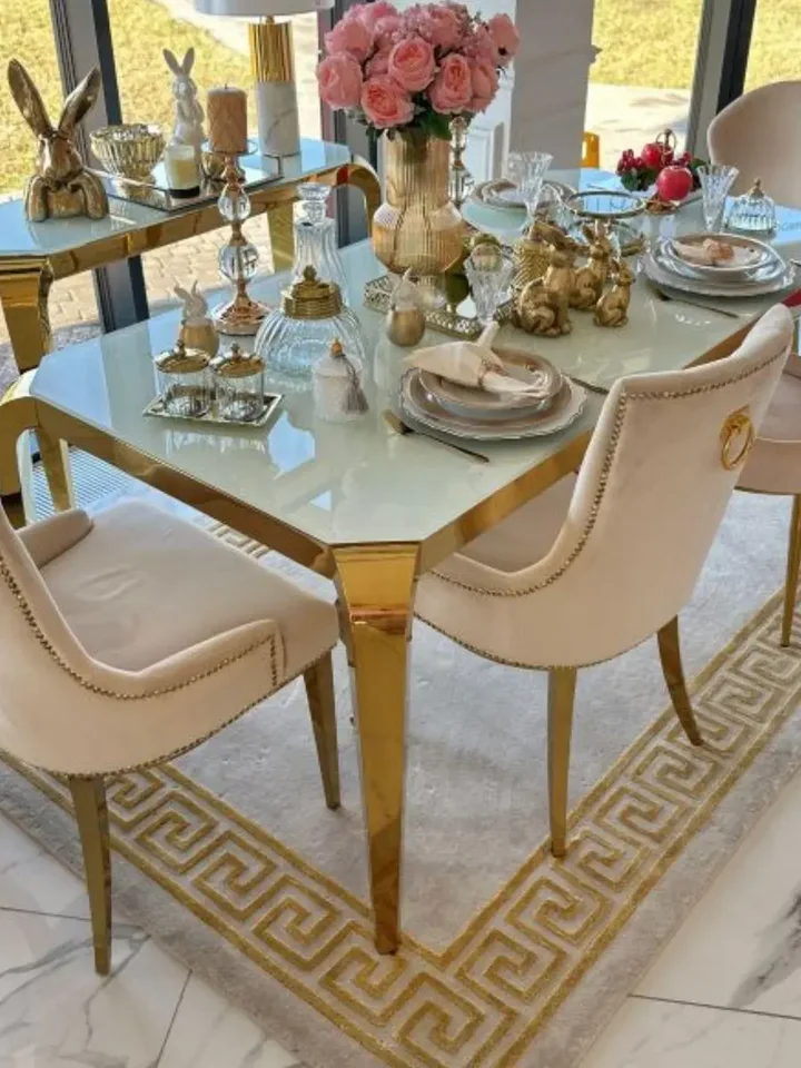 Designerski stół do jadalni, glamour, ze szklanym blatem, stalowy, złoty ELITE w jasno oświetlonym wnętrzu. Aranżacja nowoczesnego wnętrza od Primavera Home.
