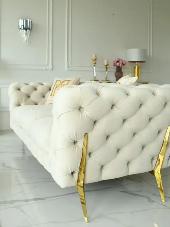 Luksusowa złota sofa pikowana DIVA GOLD widziana z kąta, prezentująca elegancję i styl. Aranżacja nowoczesnego wnętrza od Primavera Home.