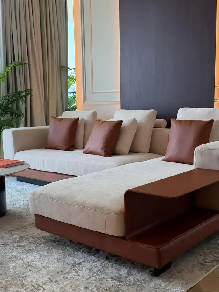 Sofa narożna z półką umieszczona przy oknie, tworząca jasną i przestronną atmosferę od Primavera Home.