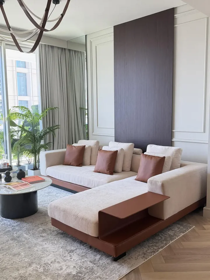 Unikalna perspektywa na sofę narożną z półką, doskonale wpasowującą się w przestrzeń salonu, przedstawiająca subtelne detale od Primavera Home.