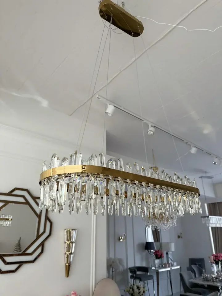 Ciepło i przytulnie dzięki Żyrandolowi BULGARI L 100cm Złoty, który wzbogaca atmosferę. Ekspozycja w salonie od Primavera Home.
