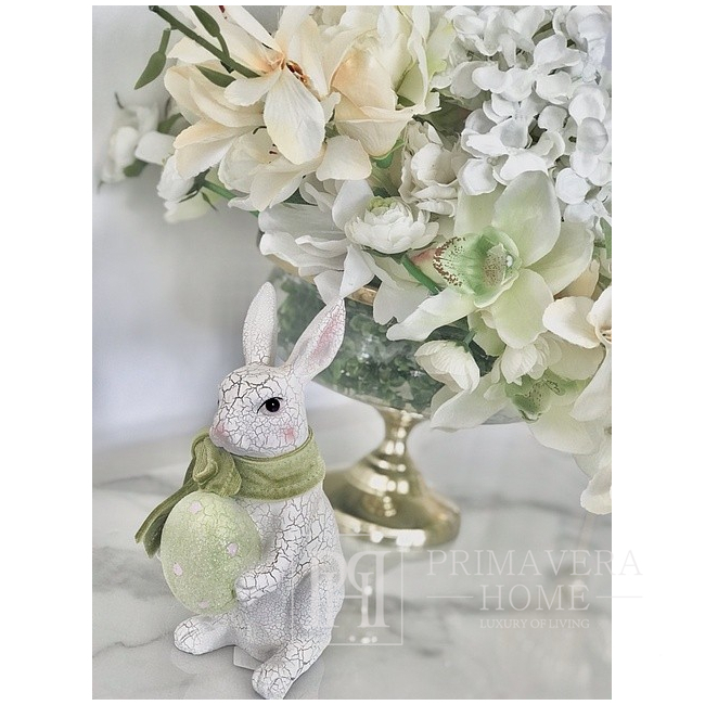 A white ceramic Easter rabbit with a green egg, with a green velvet bow