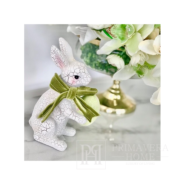 A white ceramic Easter rabbit with a green egg, with a green velvet bow